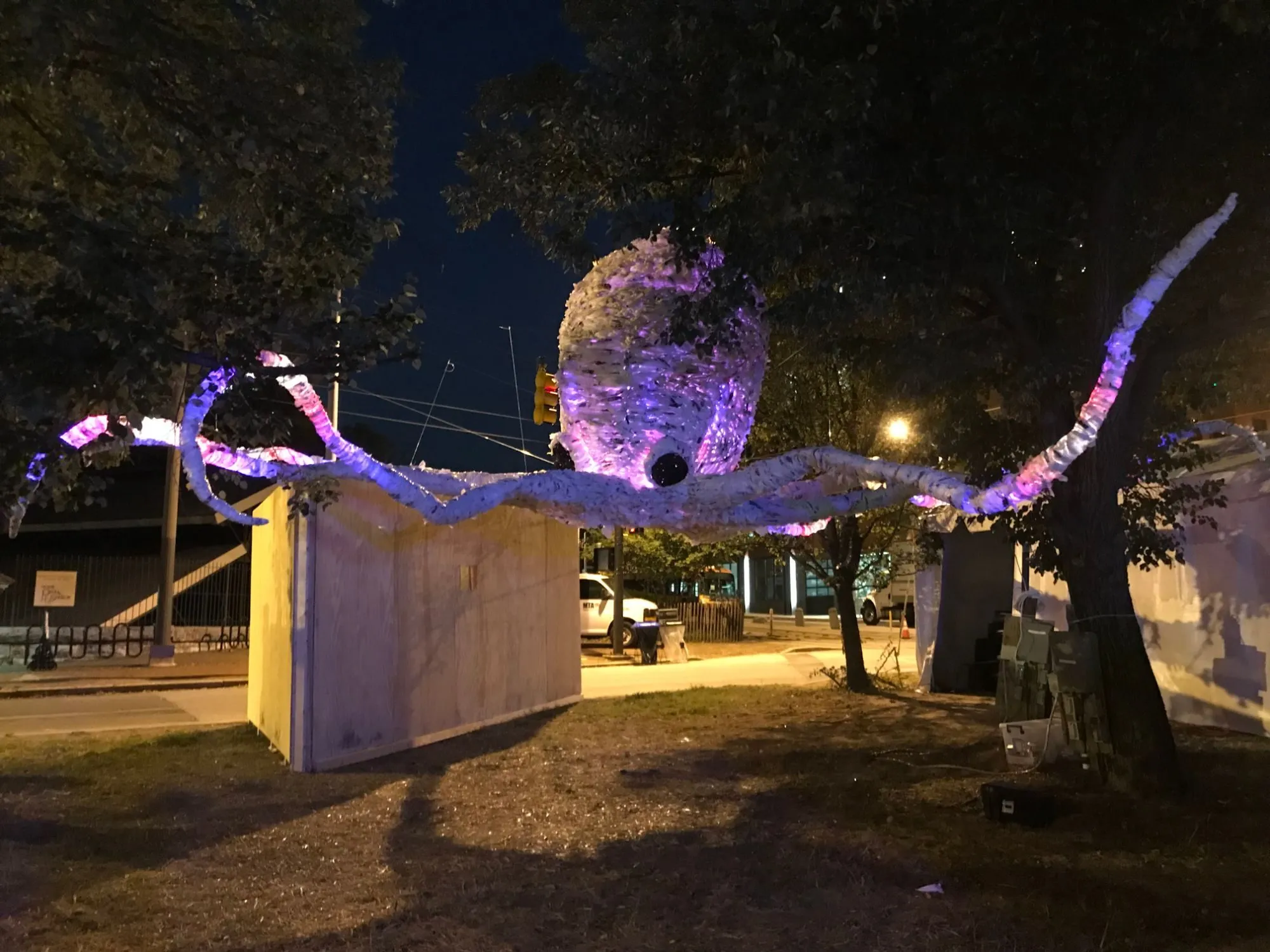 The whole sculpture lit pink and purple at night, its arms reaching out between the trees