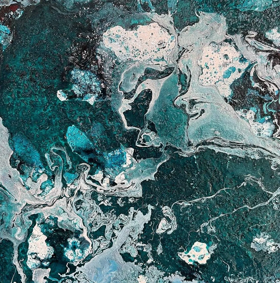 Detail of the poured surface, pale grey and white currents breaking across deep teal
