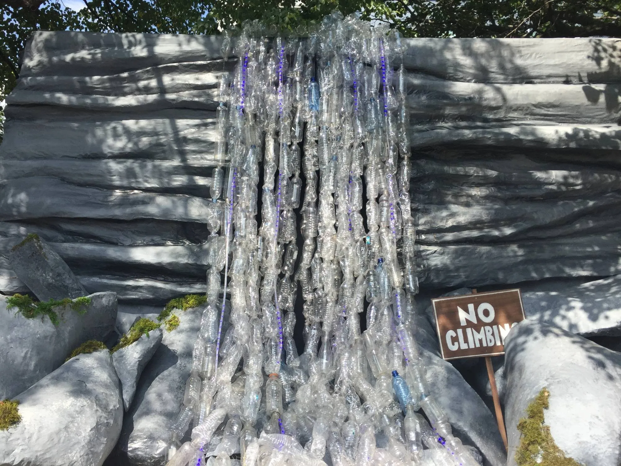 The bottle waterfall in daylight, spilling down a painted rock face