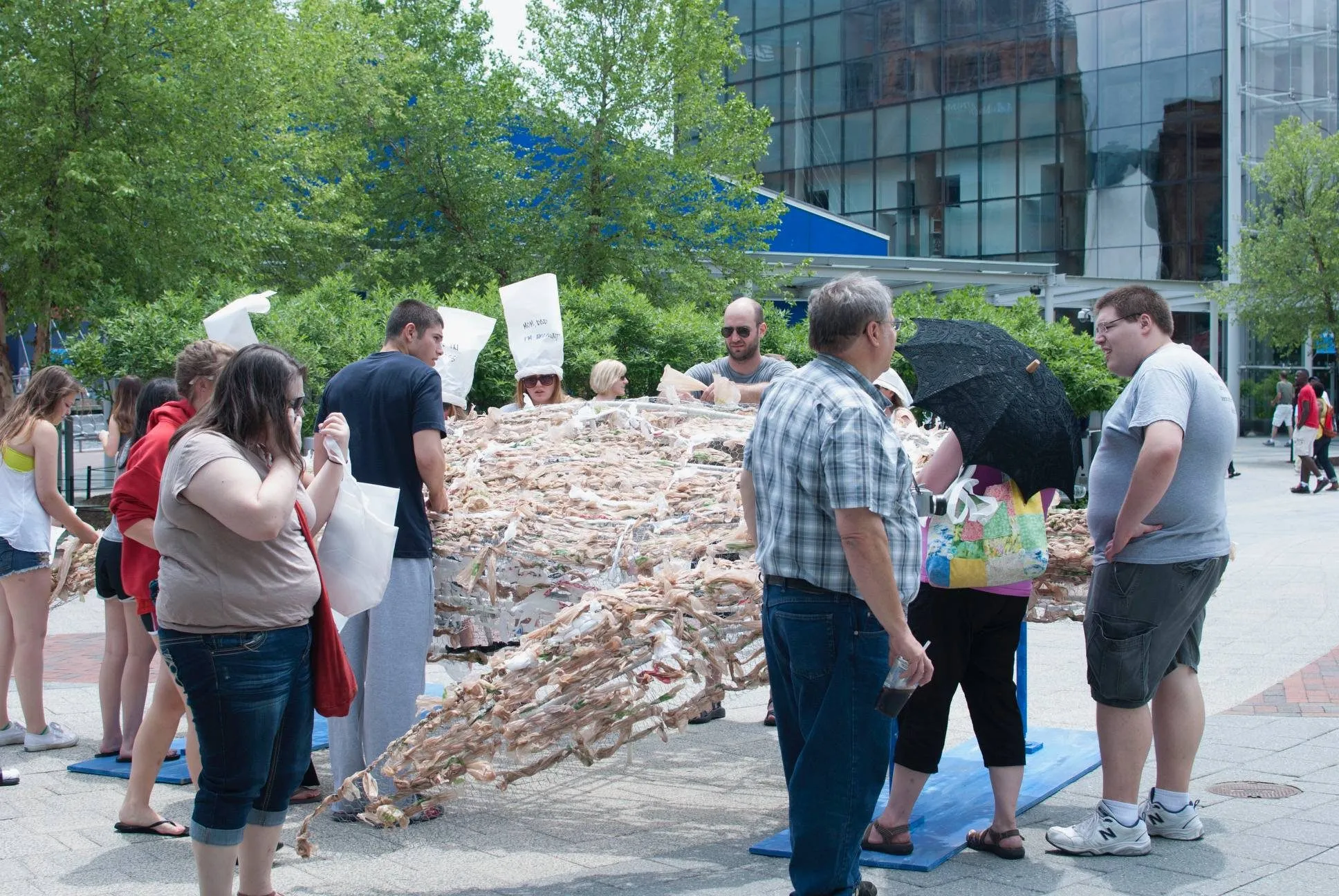 Visitors gathered around the turtle, weaving plastic bags into its shell