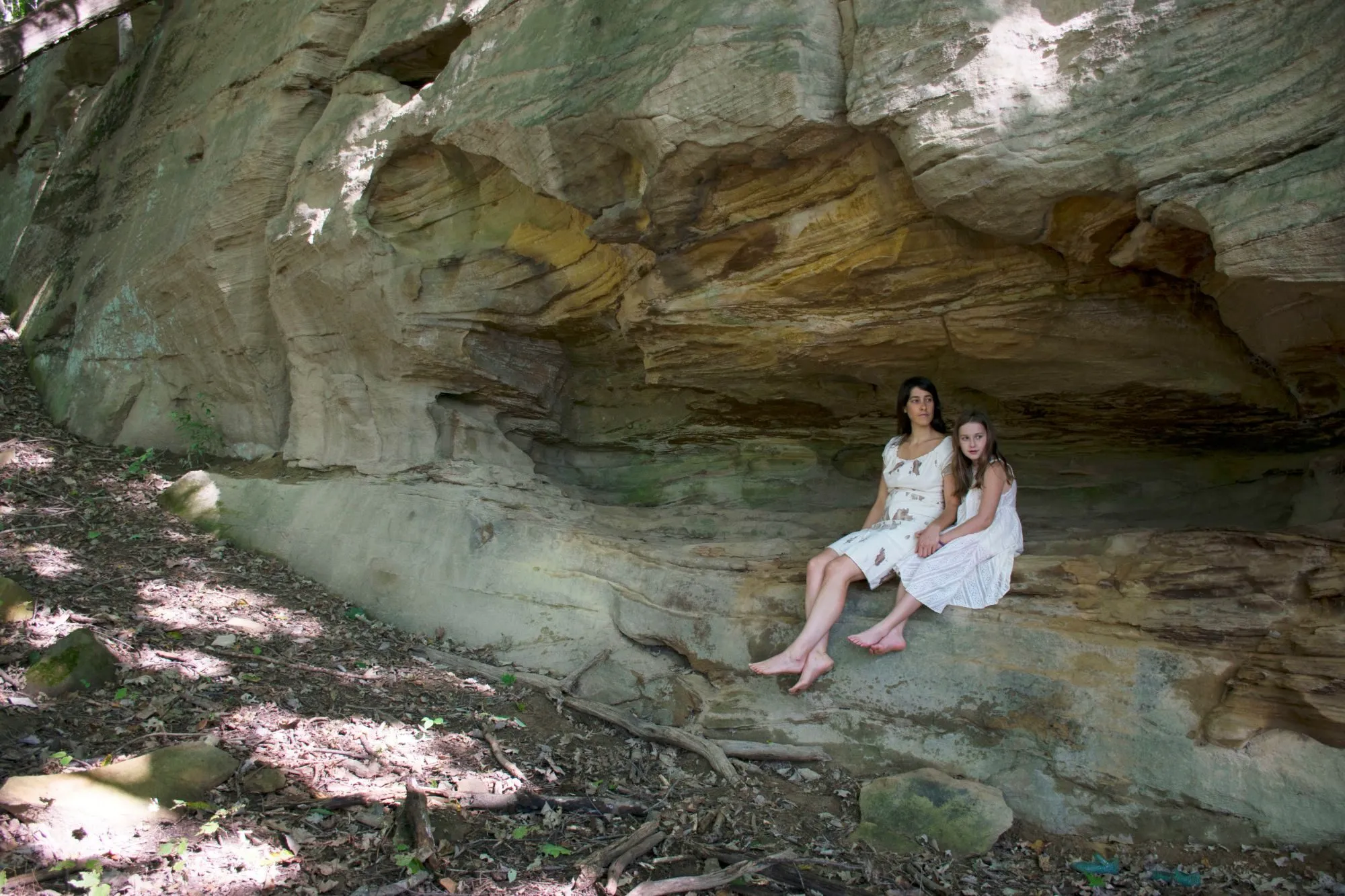 The two of us seated together on a ledge beneath a sandstone overhang, in white dresses