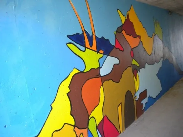 Bright interlocking shapes running the length of the tunnel wall, a horned animal's head rising out of them