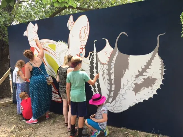 A group working on the pale, inverted form at the right end of the wall