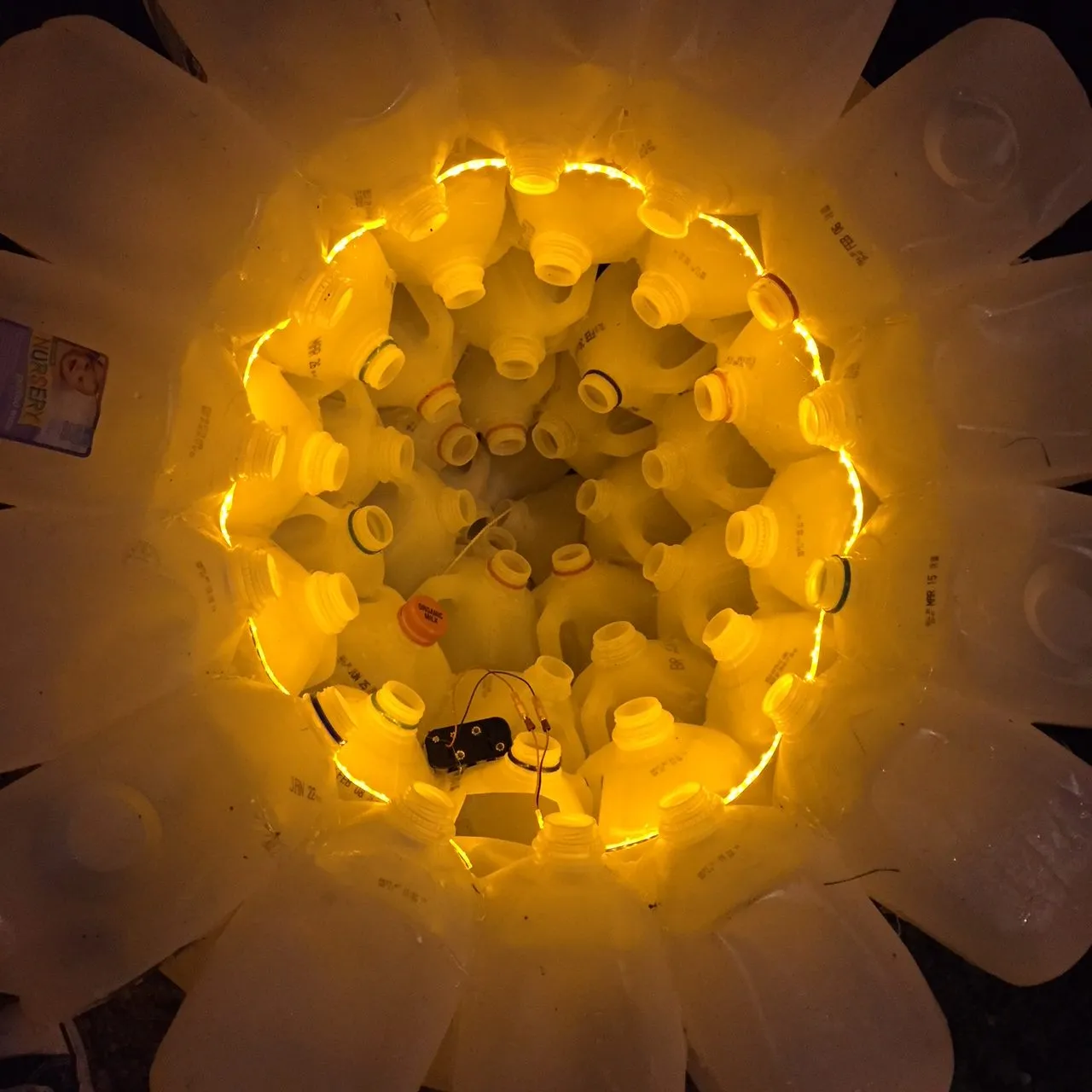 Inside a bell, a ring of LEDs and its battery pack lighting the jugs from the centre