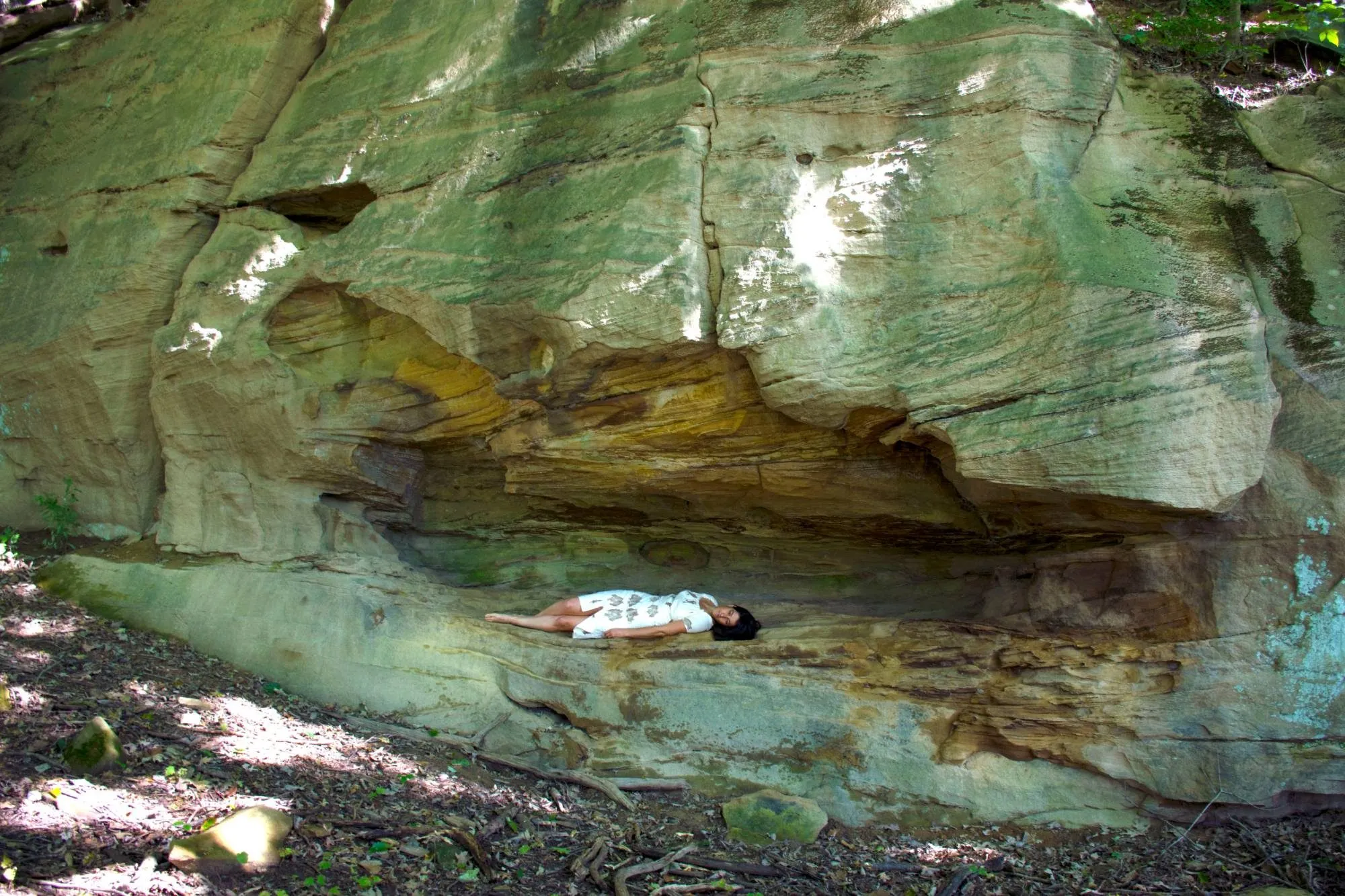Lying alone along the sandstone ledge under the overhang, in the marked dress