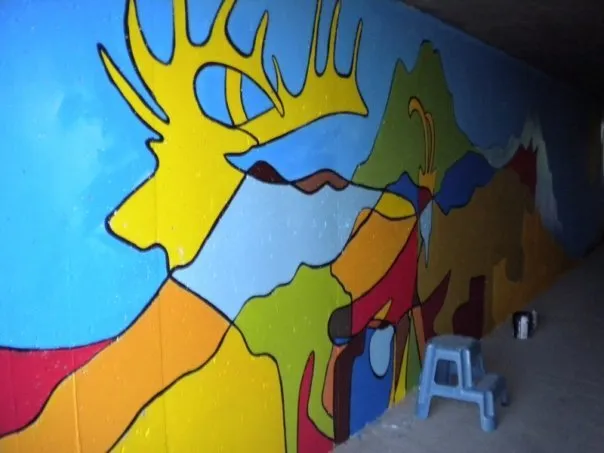 A yellow elk with wide antlers filling the tunnel wall, more animals worked into the shapes beyond it