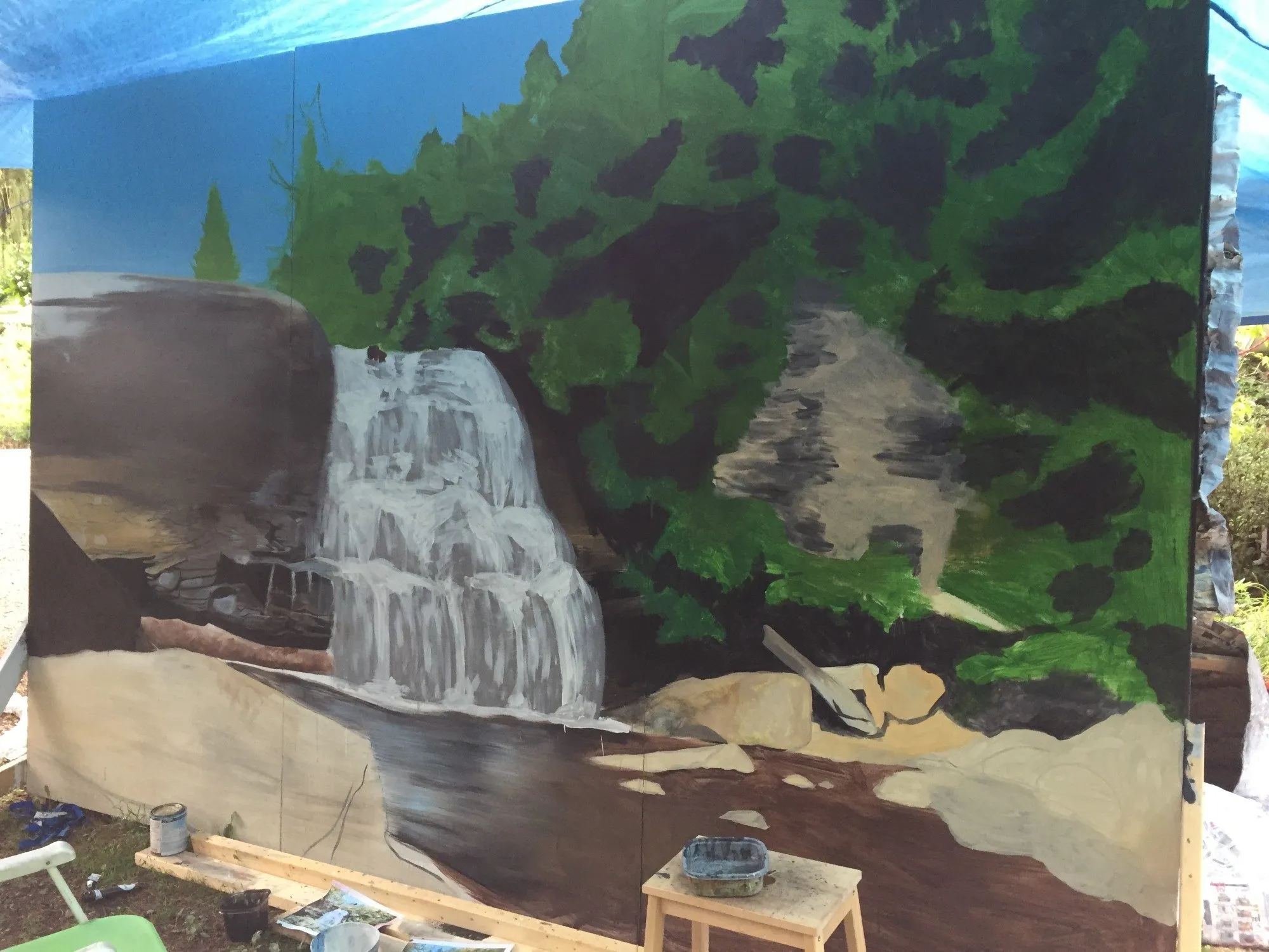 The mural well along, blue sky and green trees in, the falls painted grey and white