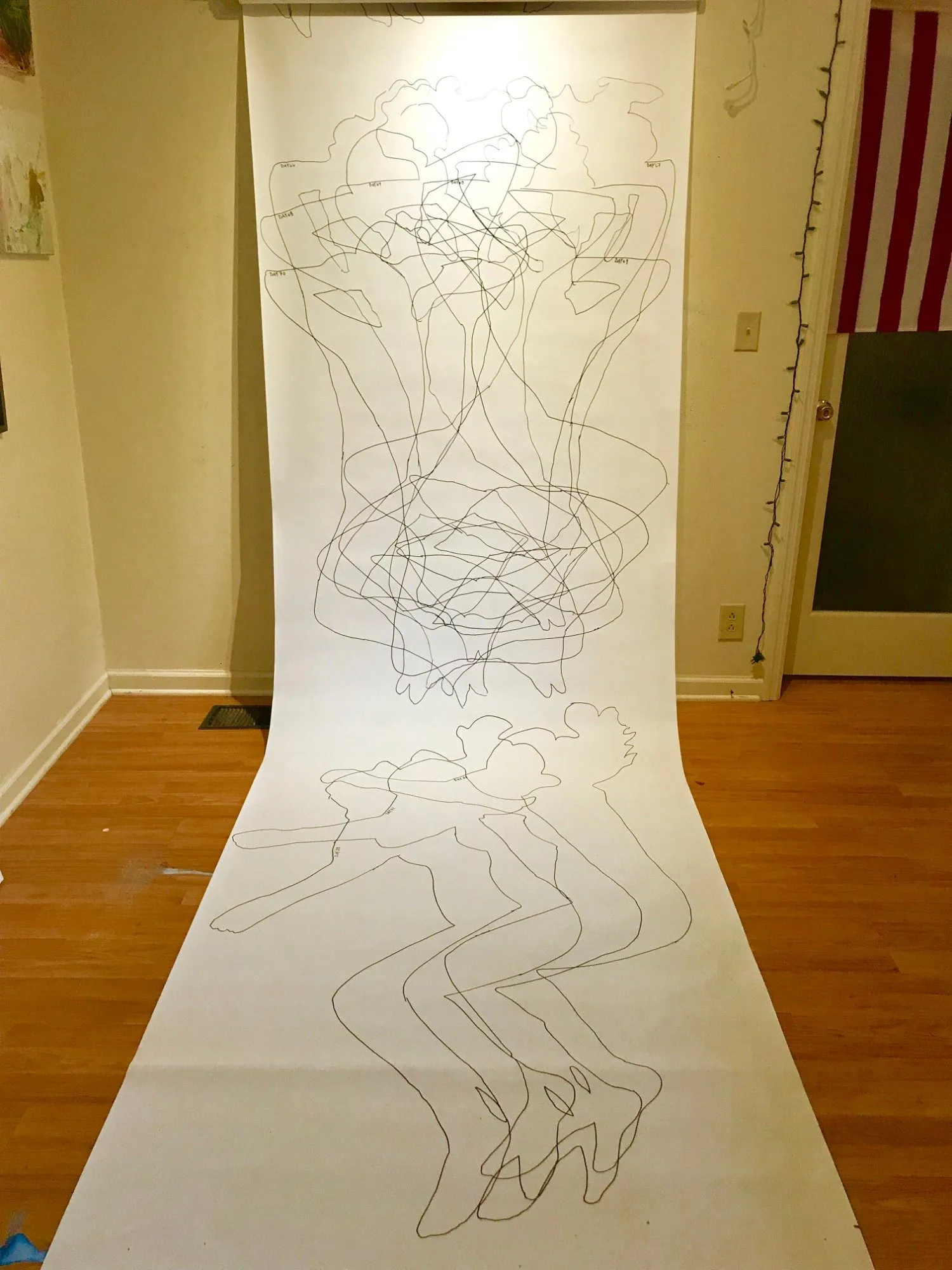 The scroll hanging from the ceiling and running out across the floor, the outlined figures reaching down its length