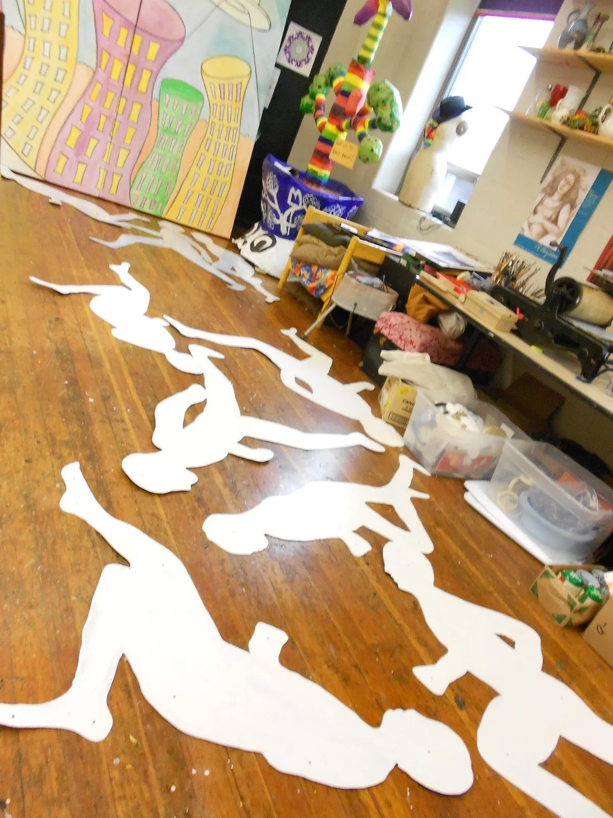 The blank cut figures laid out in a line across the studio floor