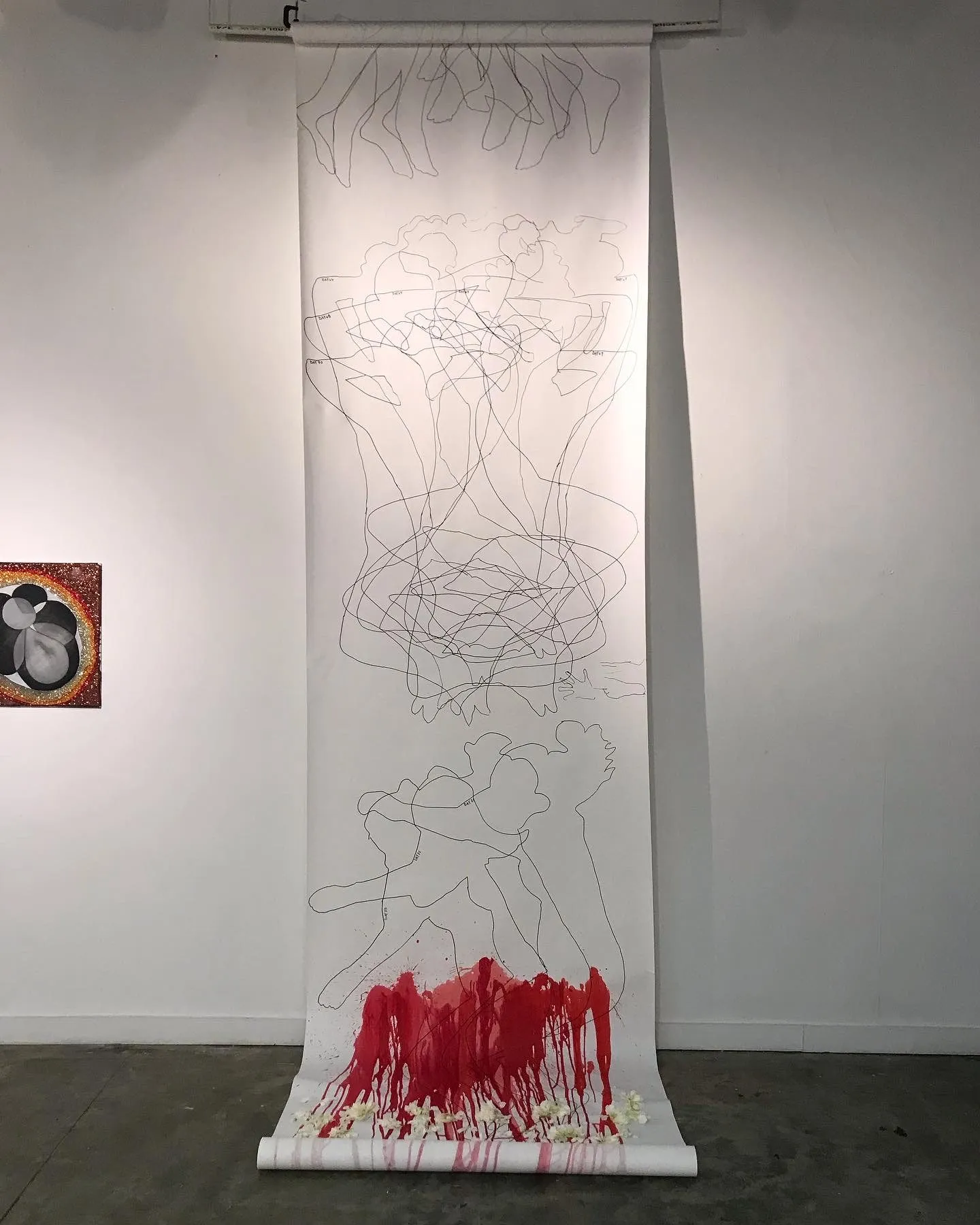 The scroll installed in the gallery, the red paint running down into the flowers at its foot