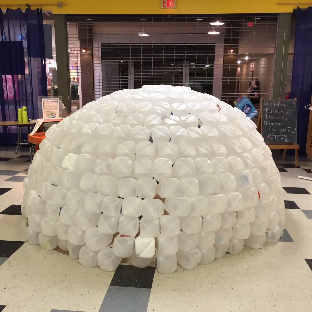 A finished bell on the museum floor, a dome built from hundreds of gallon jugs, a chalkboard sign for the Ohio Valley Museum of Discovery beside it