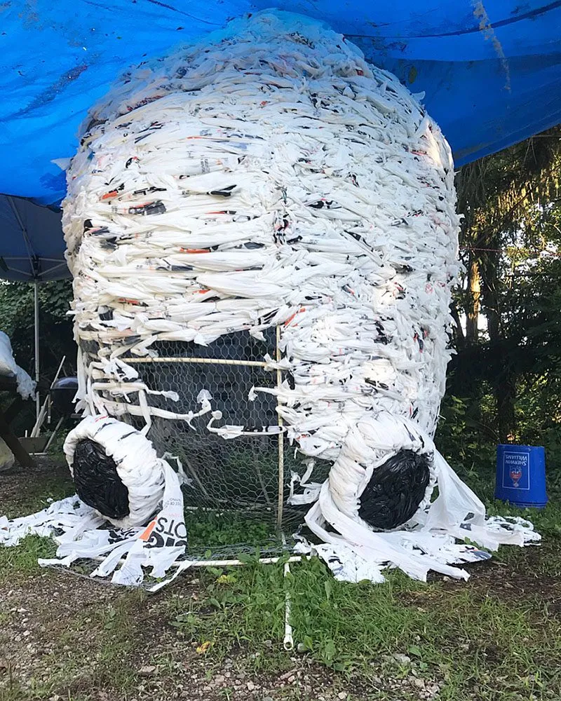 The nearly finished head under a work tarp, its eyes waiting on the ground