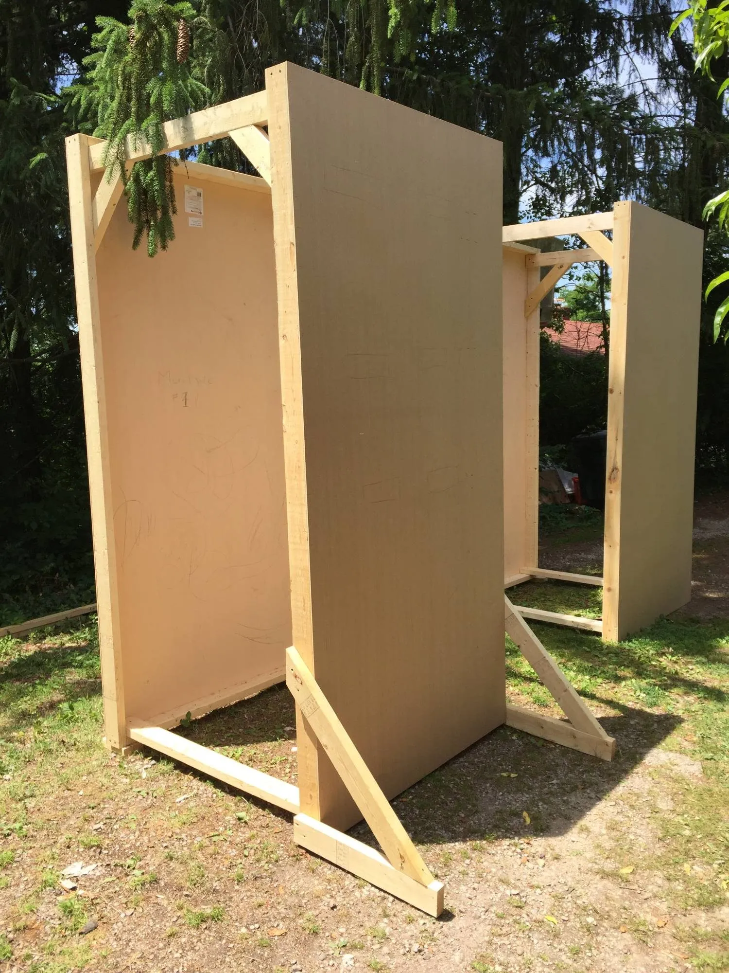 The blank facade panels braced upright in the yard, one marked "Mural Side #1" in pencil