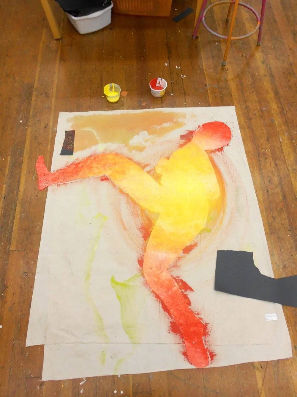One figure painted in yellow and orange on canvas, its cut stencil lying alongside