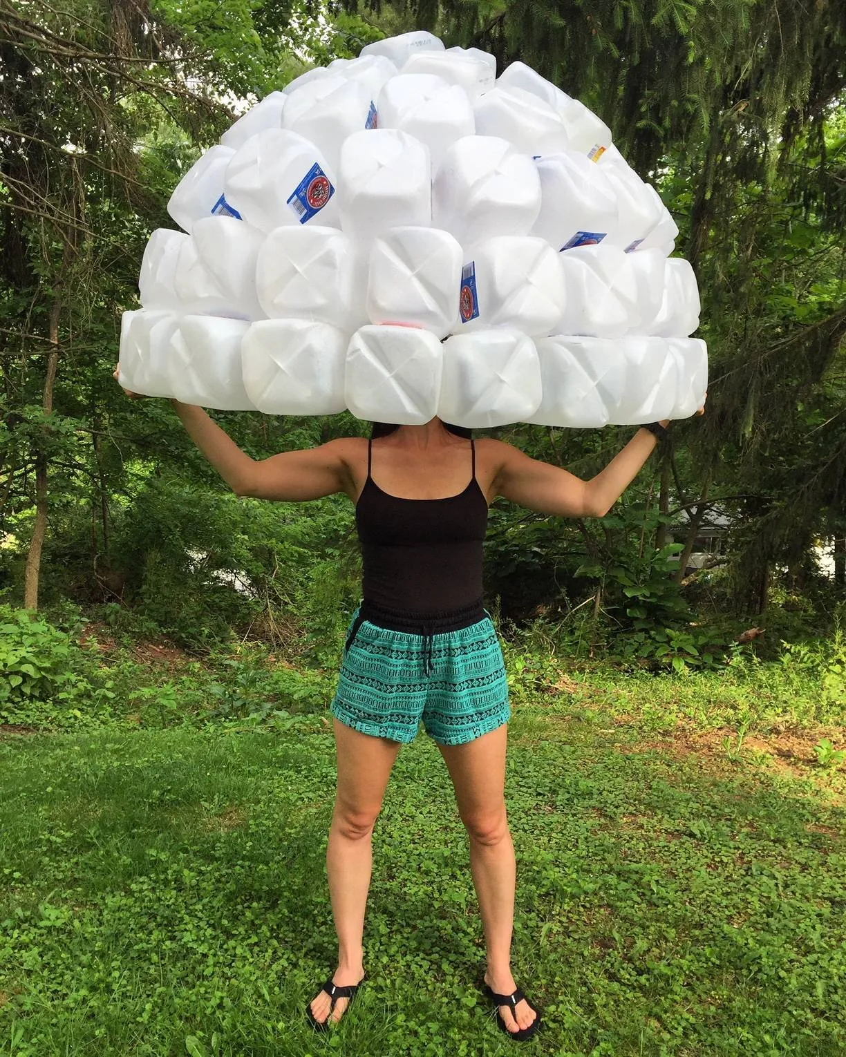 Kasey Jones outdoors holding a finished bell above her head, the dome of jugs hiding her face