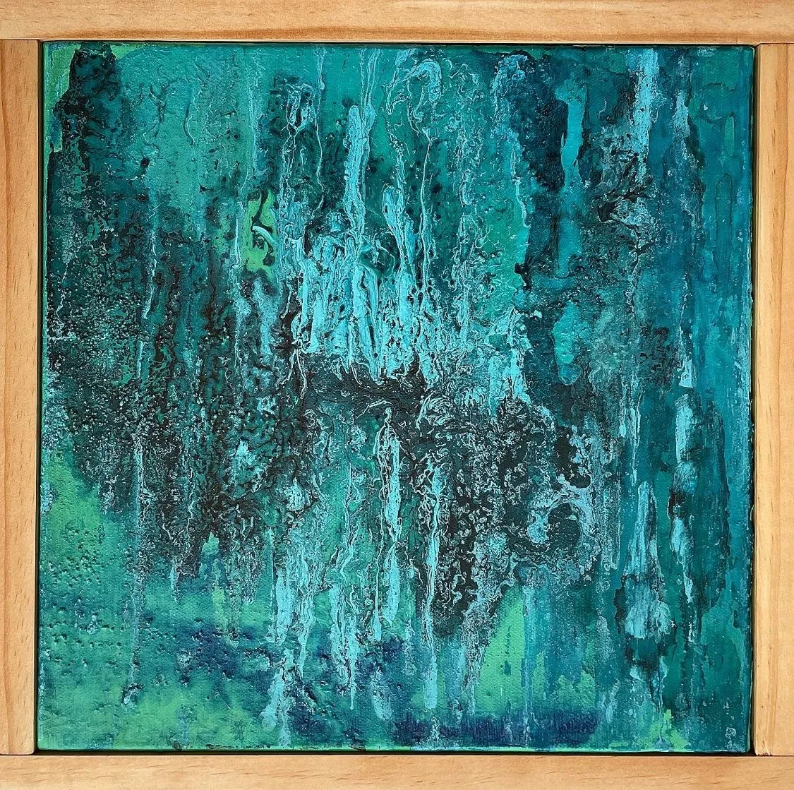 The fourth painting in a pale wood frame, teal and green running down the canvas in long curtains of poured paint
