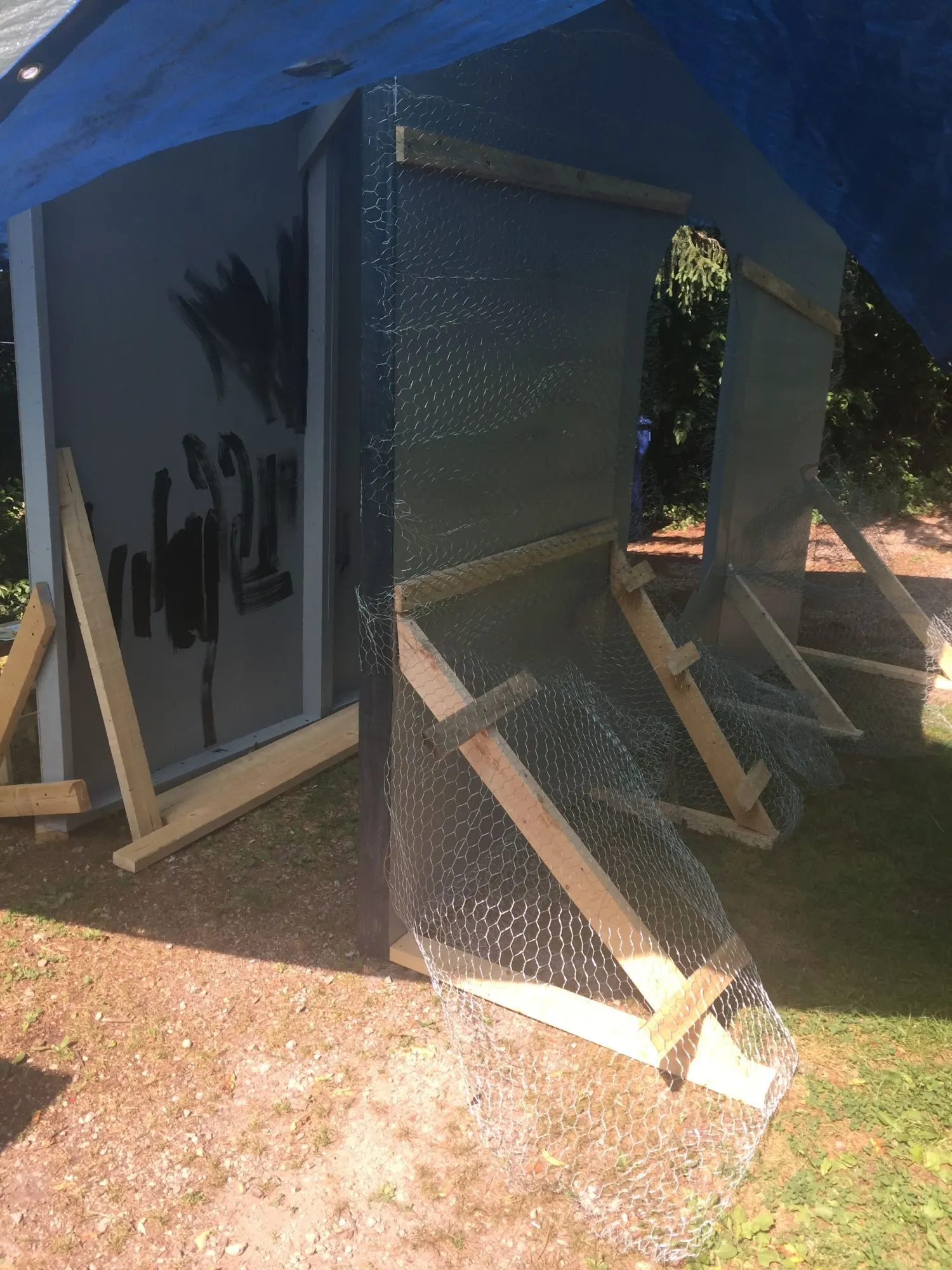 The panels under a tarp, roughed in with black brushwork and wire hung ready