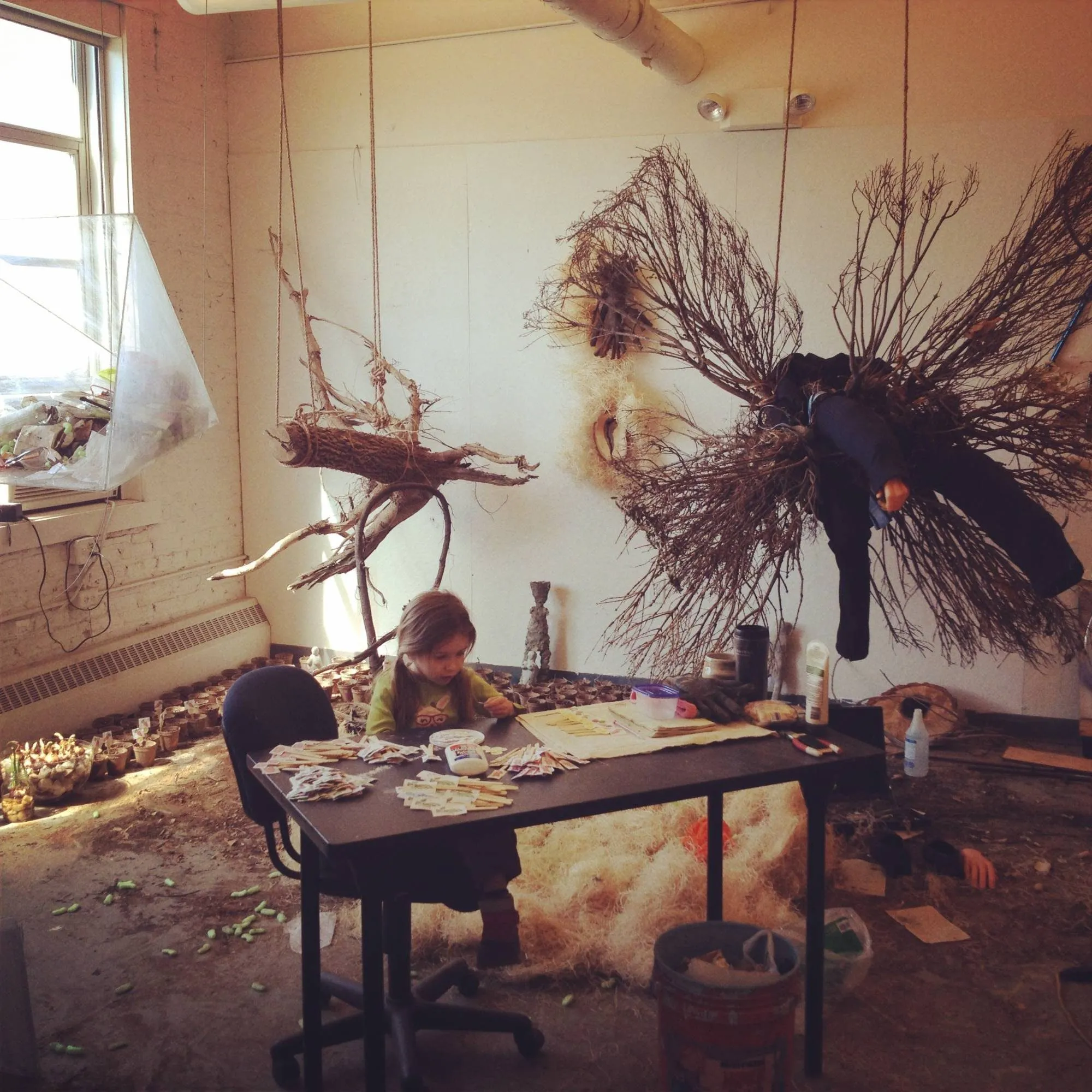 The pieces hanging from the studio ceiling, rows of small pots along the floor and my daughter working at the table