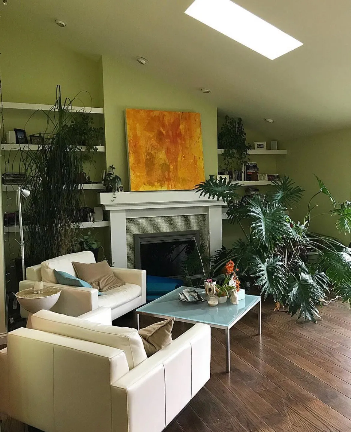 The gold painting above the fireplace in the sitting room, plants along the shelves and a skylight overhead