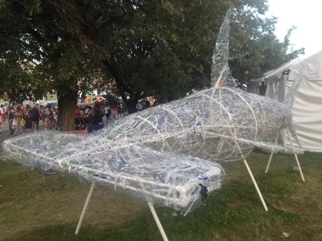 The shark from the front quarter, its hammer head and dorsal fin against the trees