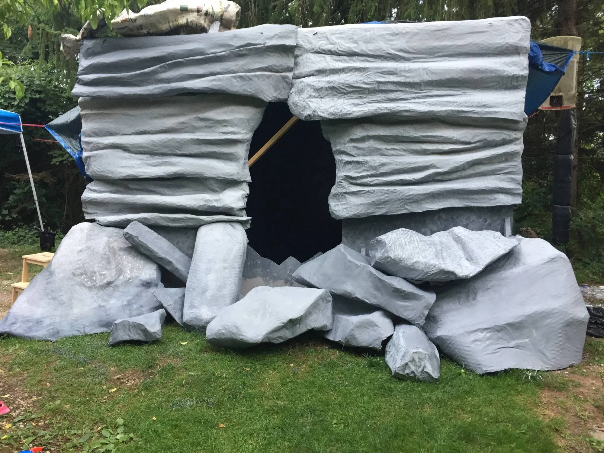 The finished facade standing in the yard, boulders piled around the cave opening