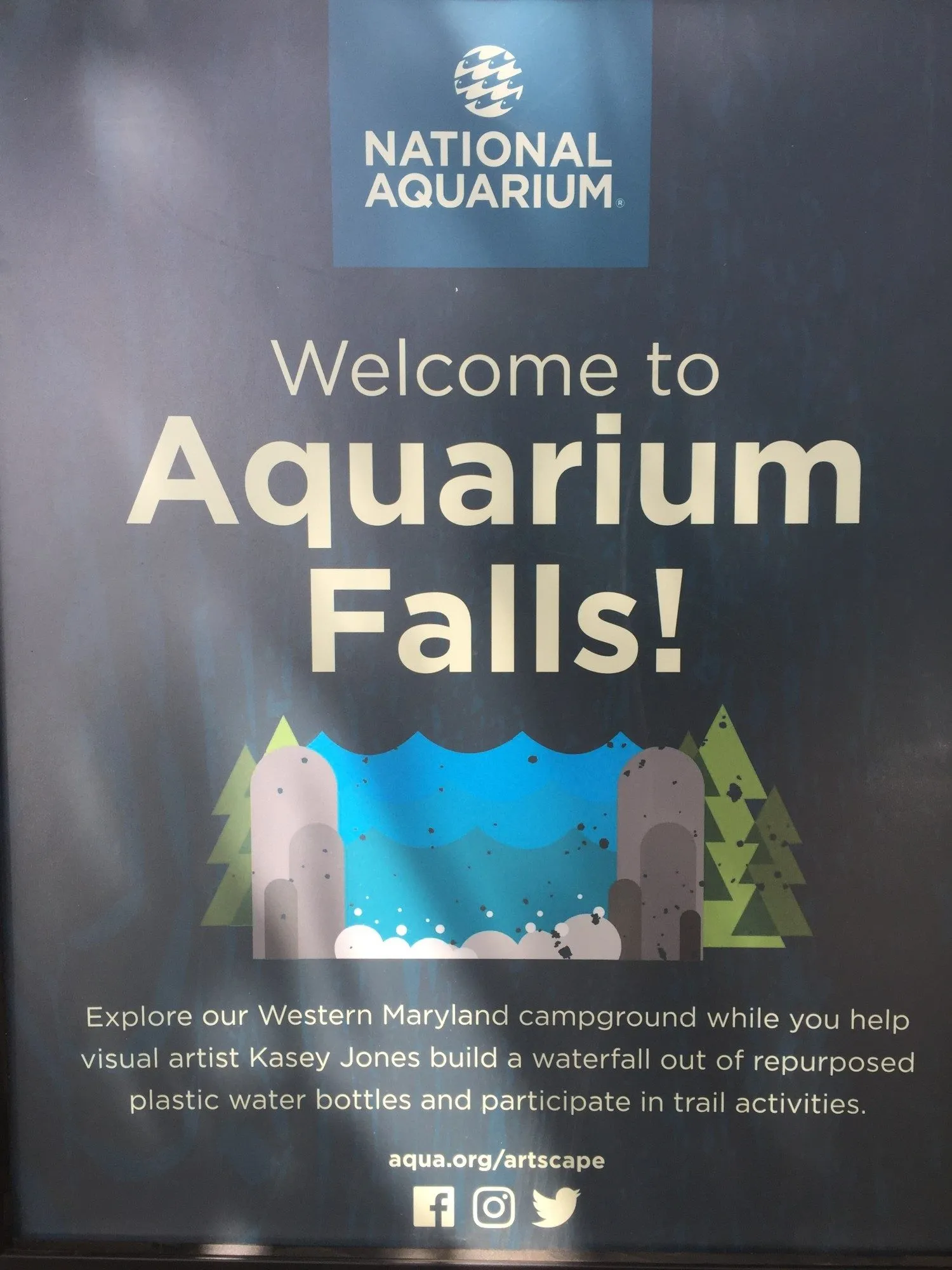 A National Aquarium poster reading "Welcome to Aquarium Falls! Explore our Western Maryland campground while you help visual artist Kasey Jones build a waterfall out of repurposed plastic water bottles"