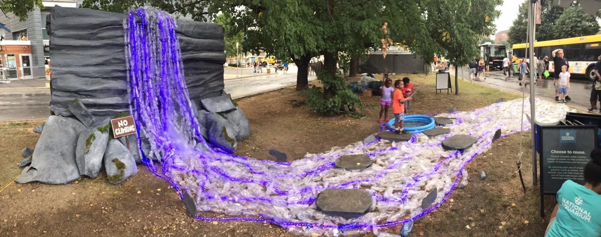 The whole installation at the festival, the lit waterfall spilling into a stream of bottles with stepping stones across it and children playing