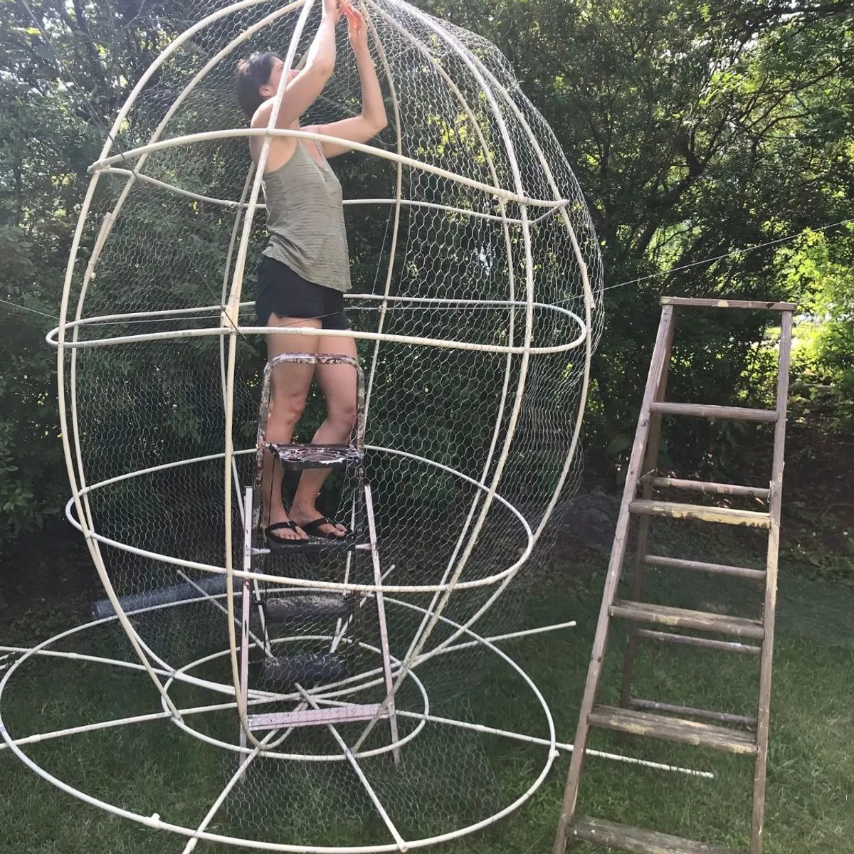 Kasey wiring the chicken wire frame of a large sculpture in her yard
